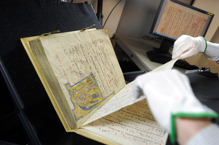 Das Bild zeigt eine Mitarbeiterin bei der Digitalisierung einer mittelalterlichen Handschrift.