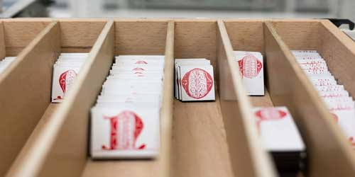 Kleine weiße Magnete mit Buchstaben aus Initialen sind in ein Holzfach sortiert.